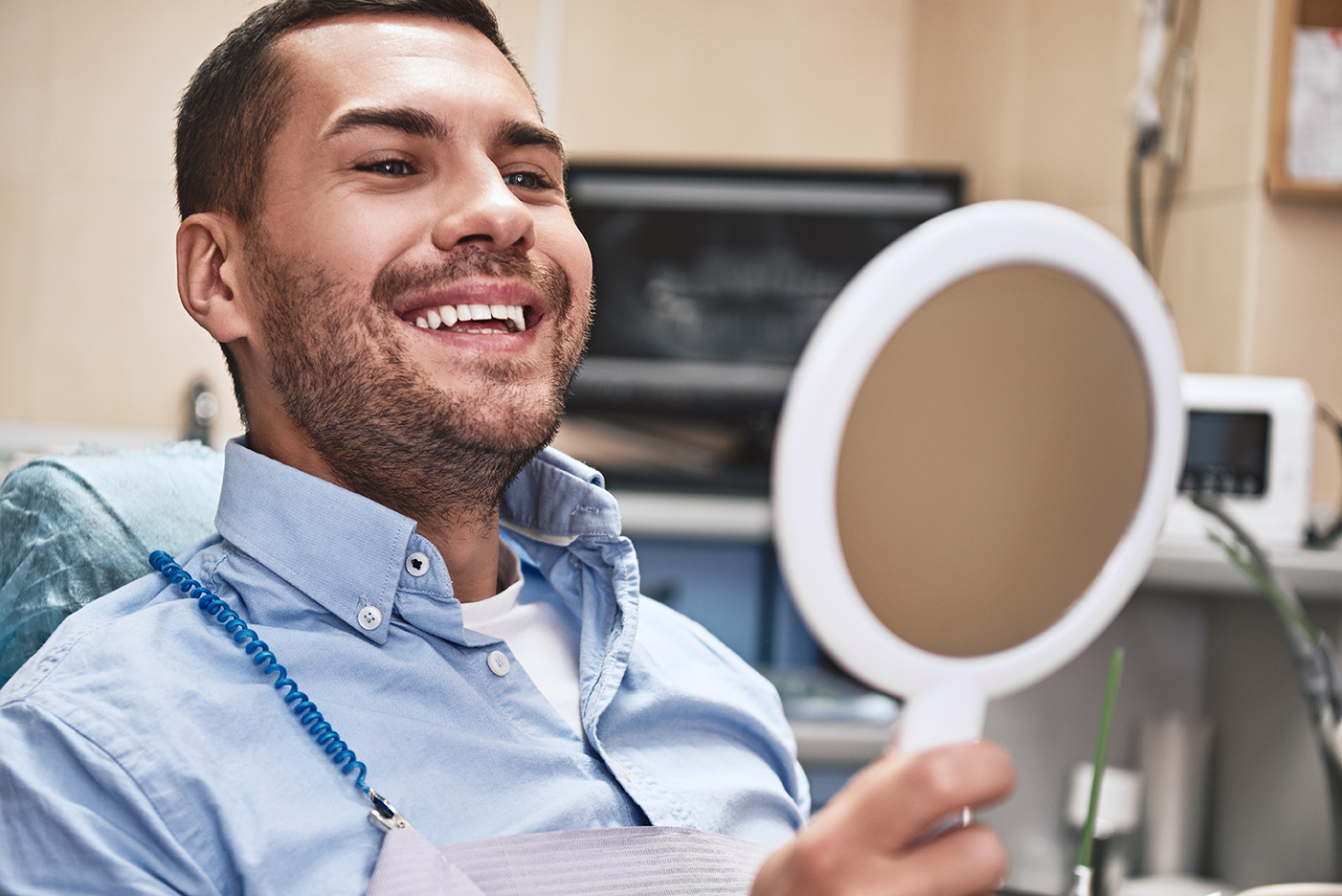 man smiling in a mirror after wisdom tooth removal at scholes family dental